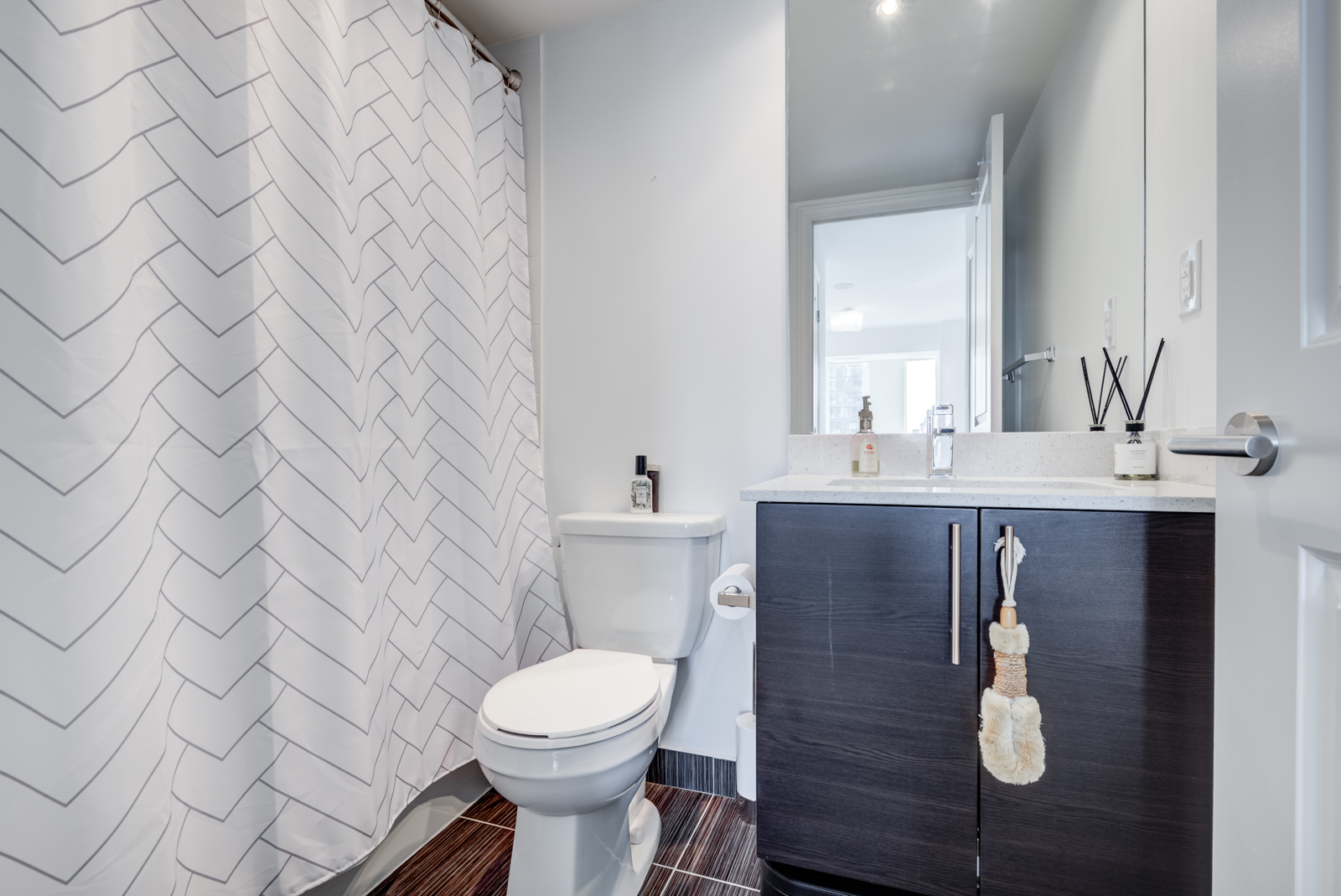 Master bath with closed white curtain, toilet and large vanity.