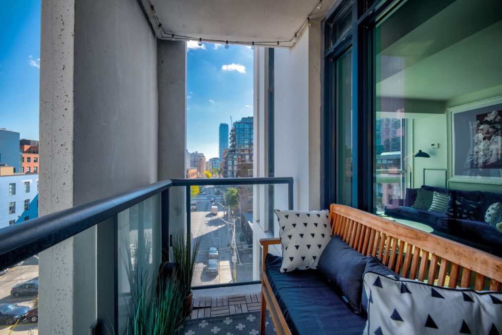 17. balcony with glass panels wooden bench with pillows overlooking sherbourne adelaide toronto