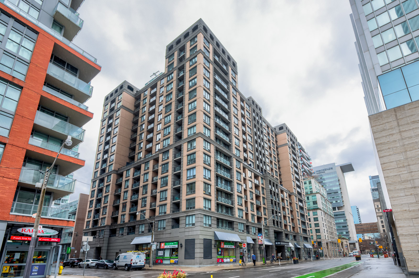 View of 140 Simcoe St E, a pink and gray stone condo, from across the street.