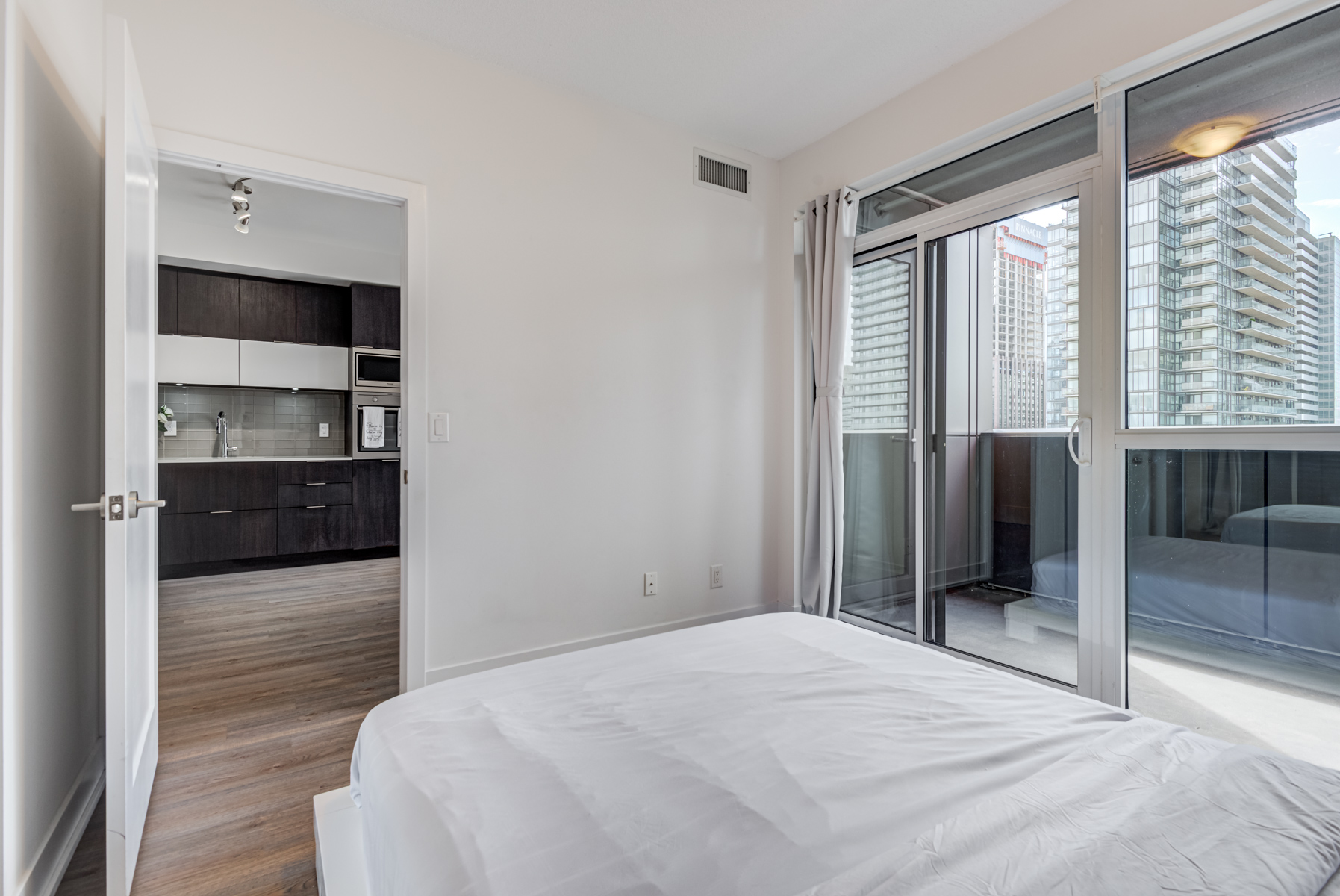 Condo bedroom with walk-out balcony showing Toronto in background.