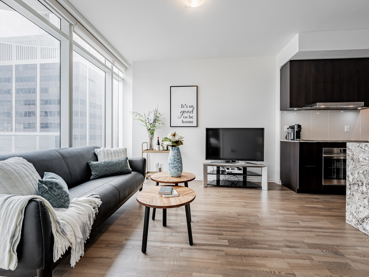 1 Bloor St E Unit 3409 living room with sofa, table, TV and plants.