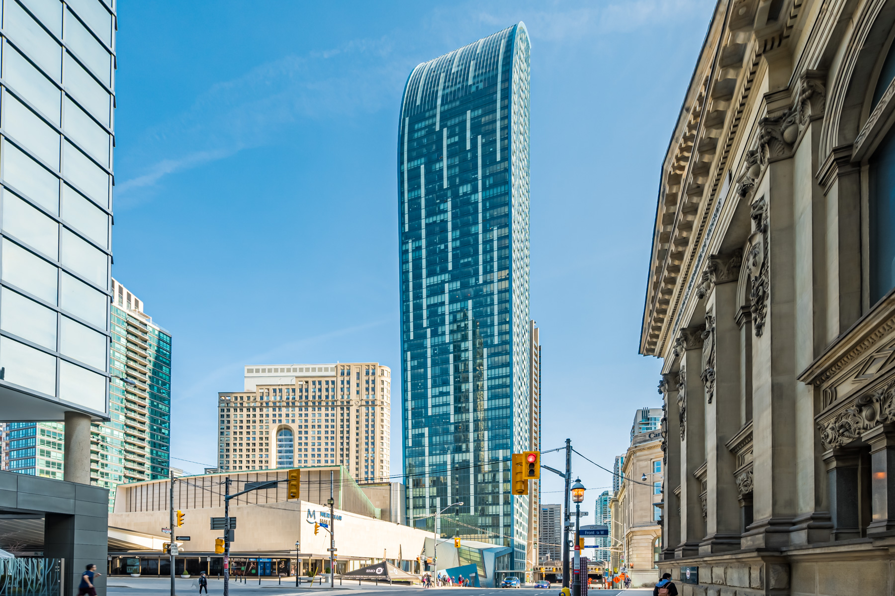 Long distance photo of L Tower condo in Toronto, showing its blue glass and curving form.