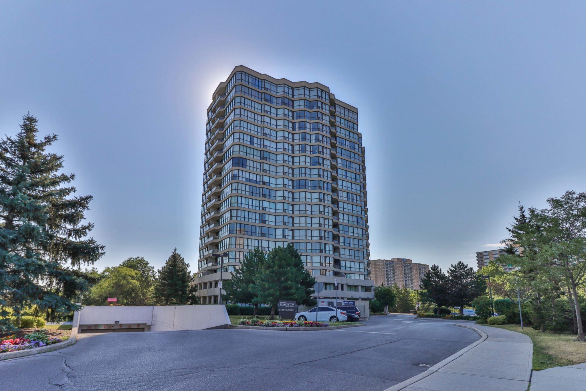 Across the street view of 5 Rowntree Rd, a mid-rise condo of gray concrete and blue glass.