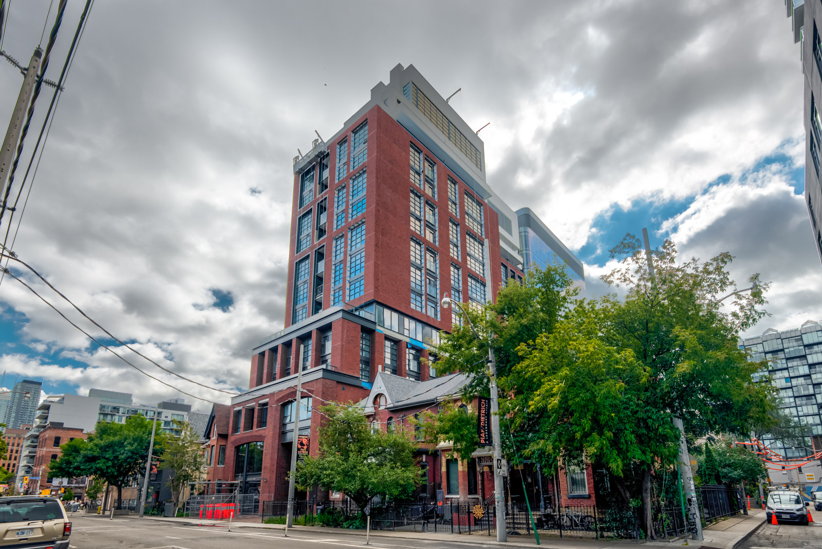 Across the street view of Kingly Residences with red-brick and blue-glass in King West Toronto.