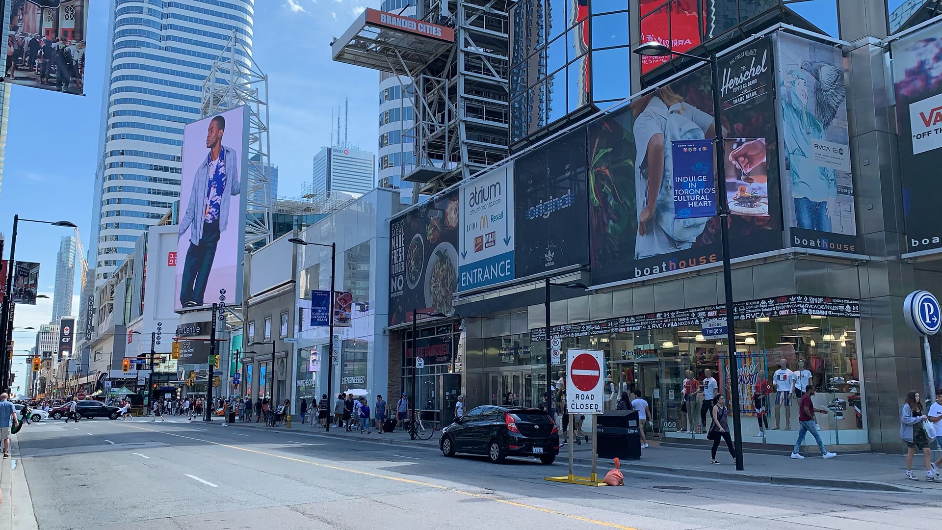 Photo of Yonge and Dundas in Toronto with large billboards people walking on street.