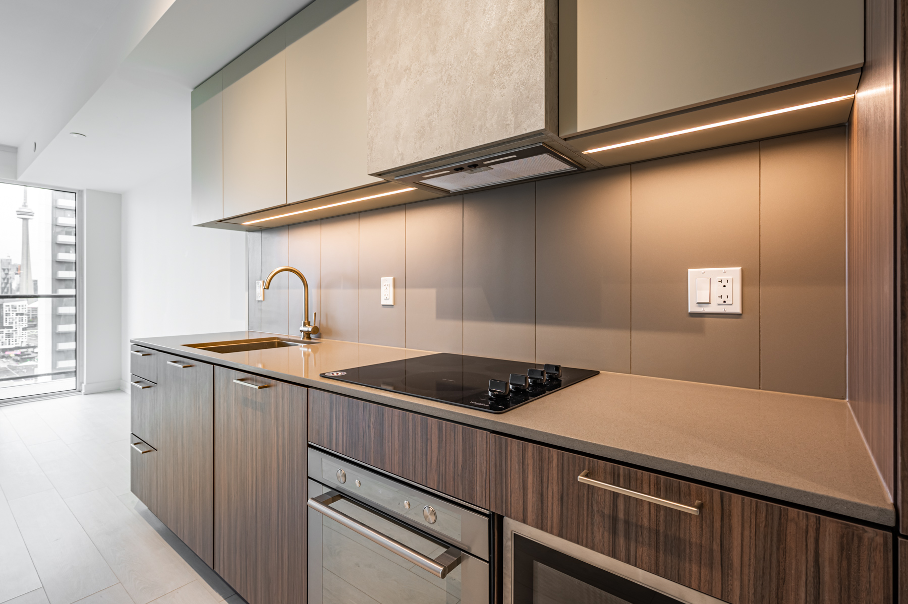 Condo kitchen with stone counters, dark cabinets and backsplash.