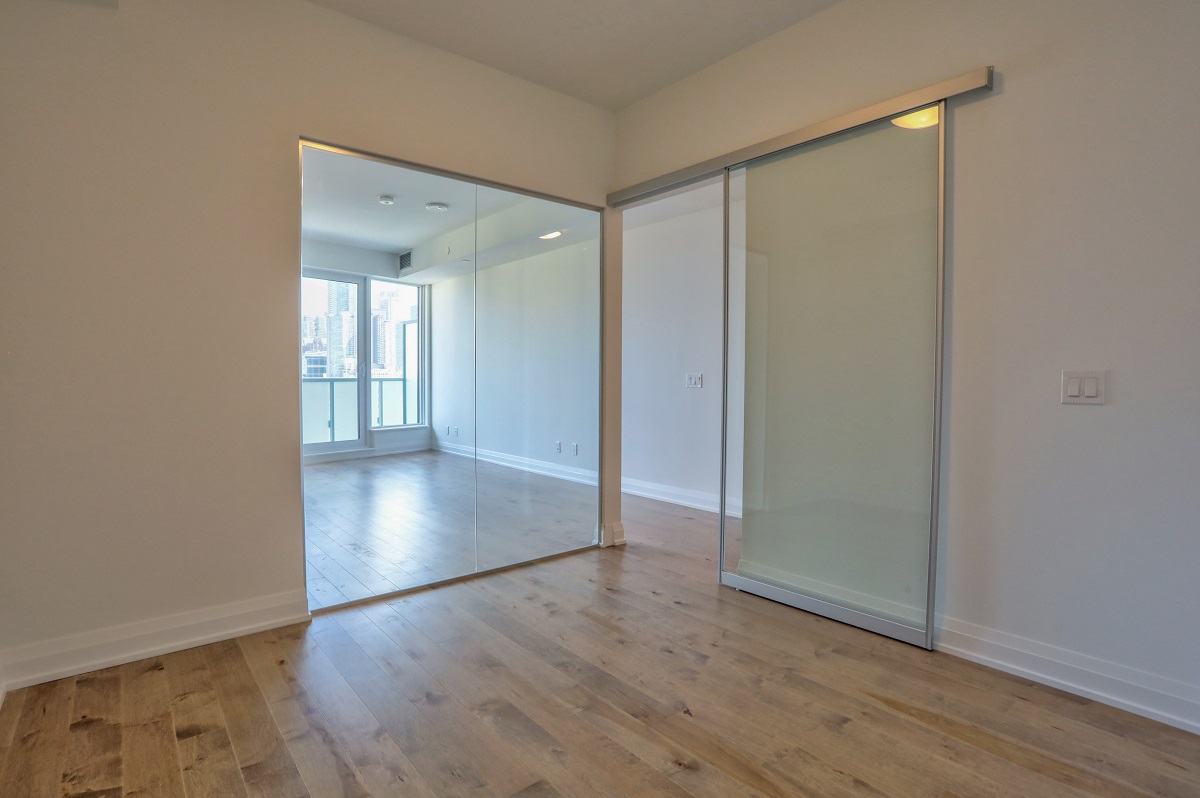 403 Church St Suite 1101 master bedroom with sliding door and mirror walls.