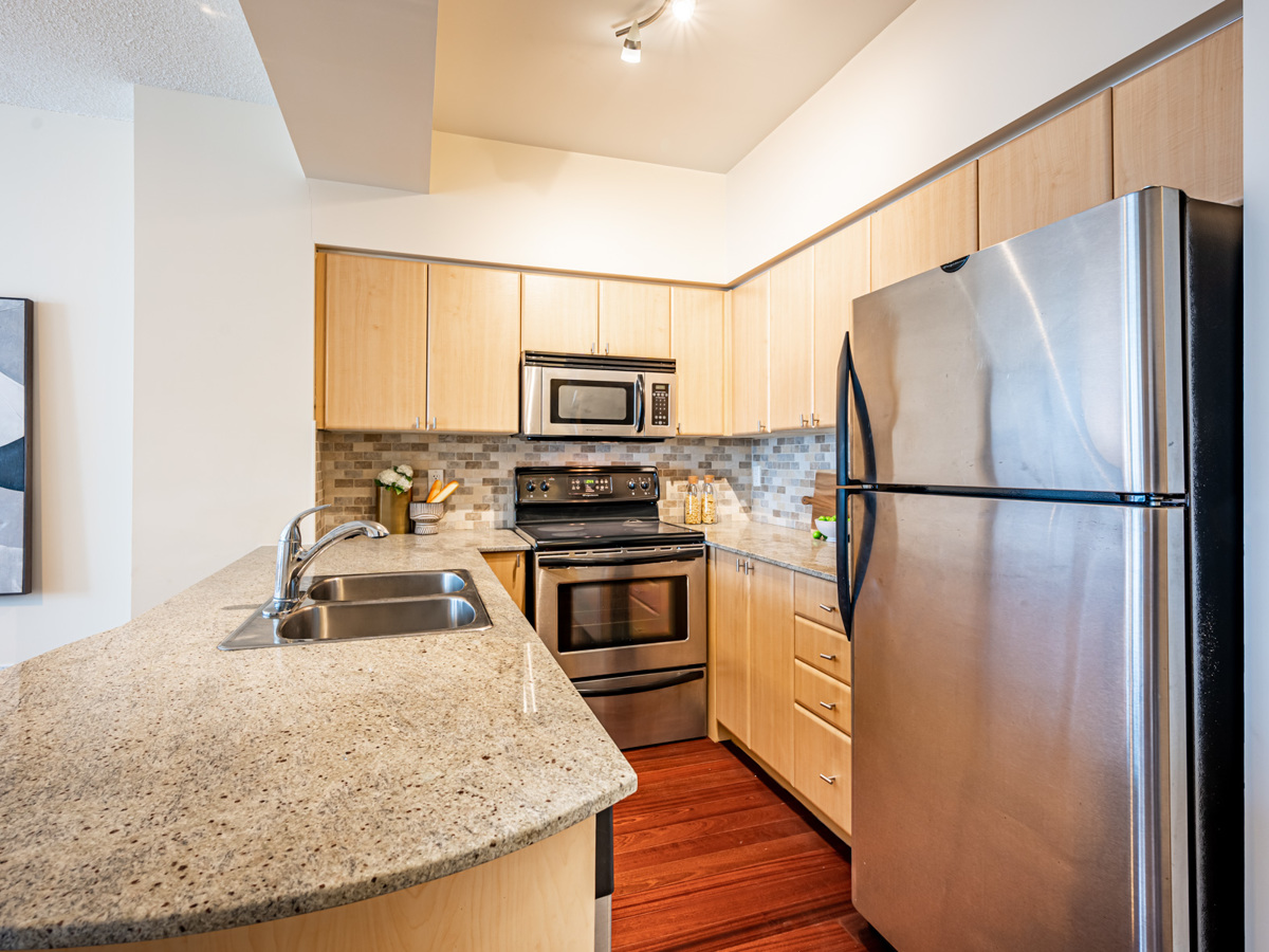 U-shaped condo kitchen with beige cabinets and drawers.