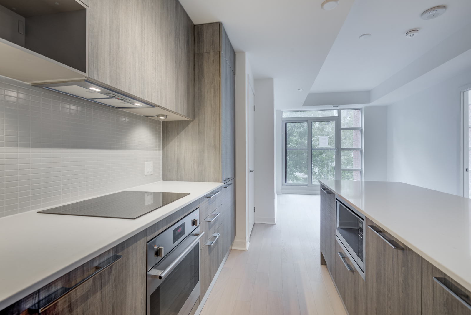  Kitchen cabinets and appliances to left, kitchen island to right, and living room in distance.