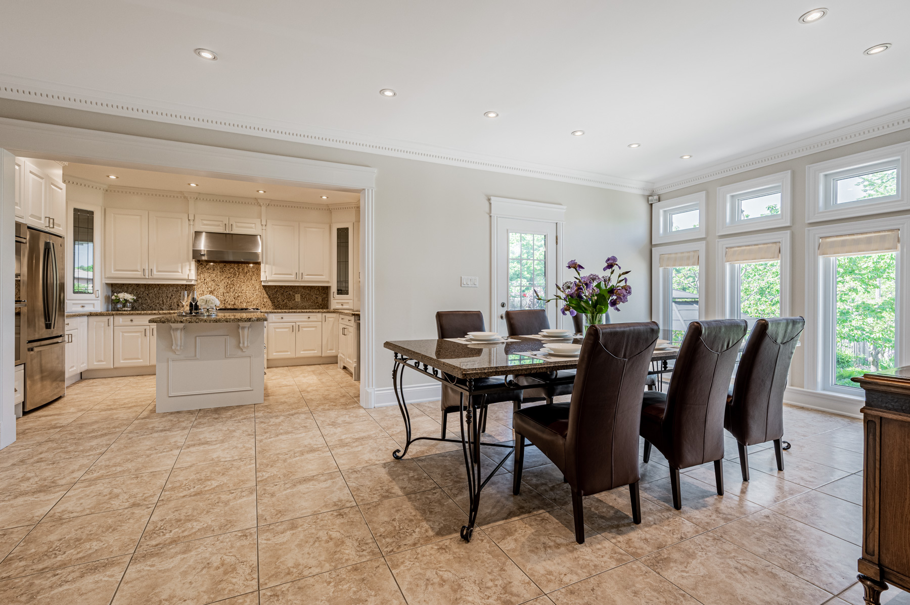 House breakfast area lit by large windows overlooking backyard.