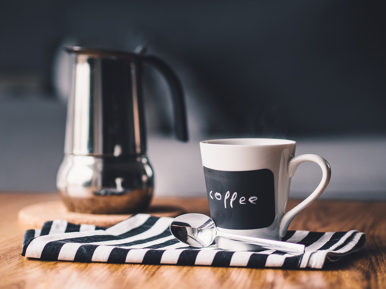 Table with coffee mug, spoon and pitcher.