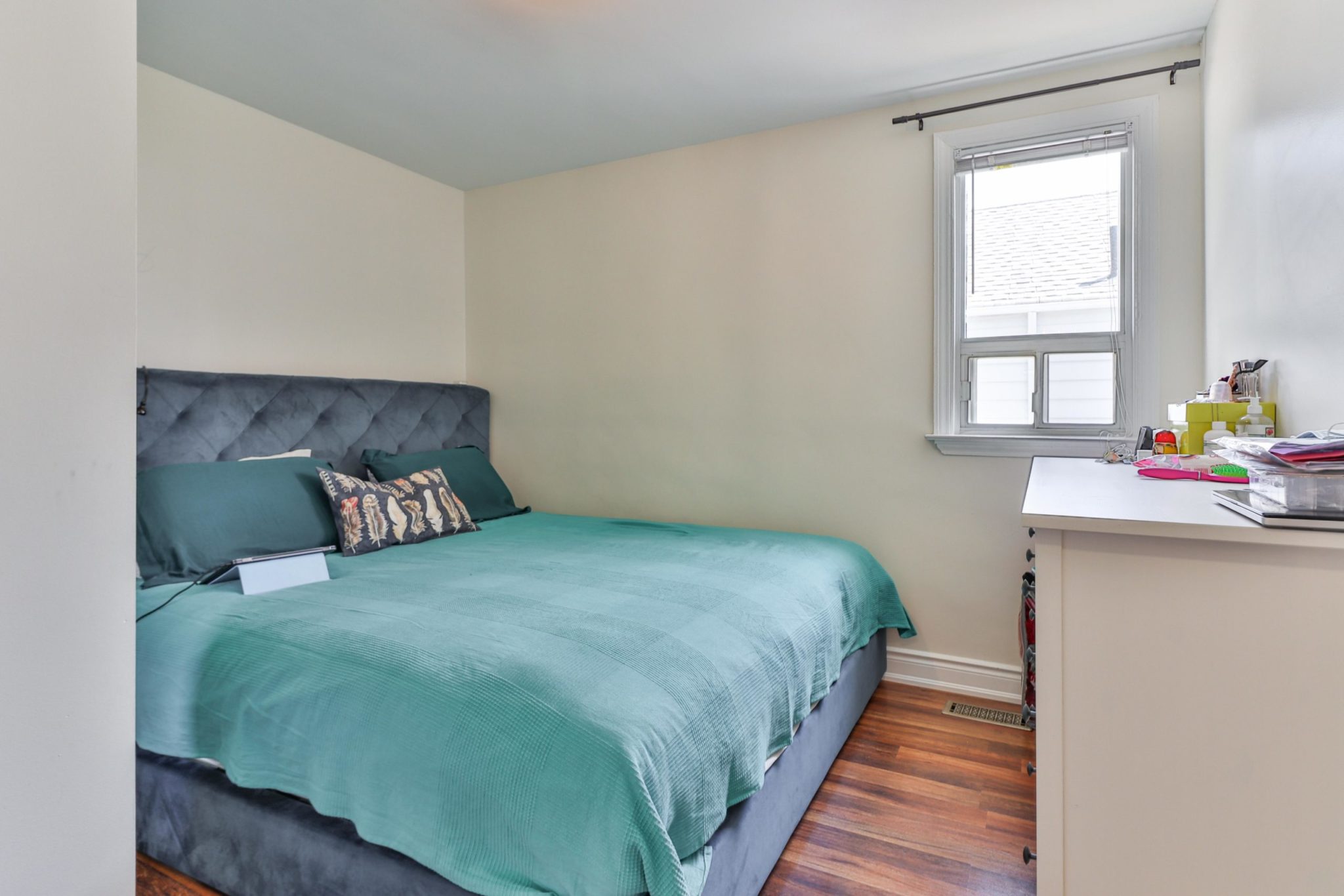 117 Phillip Ave master bedroom with queen-sized bed, blue sheets, laminate floors and window.