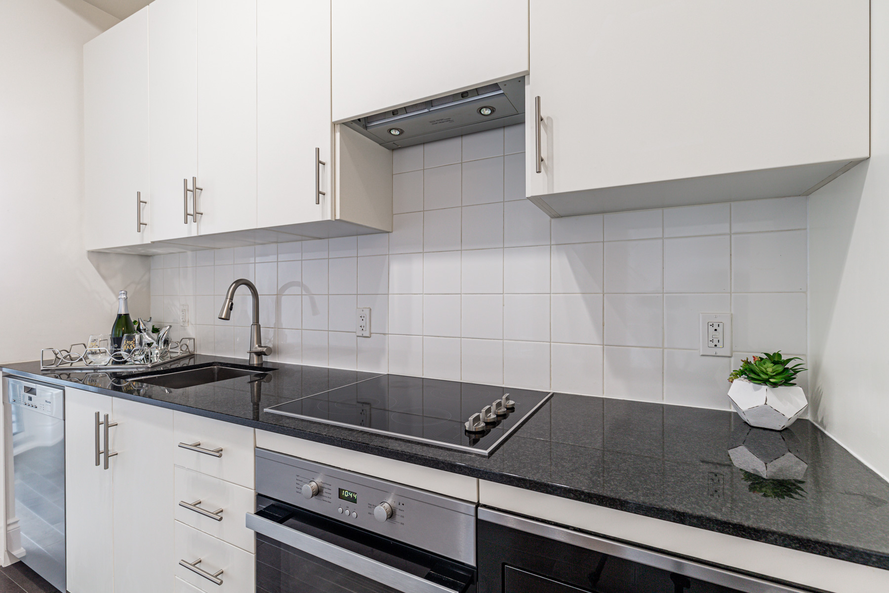 23 Glebe Rd W condo kitchen with white cabinets, black granite counters and white ceramic backsplash.