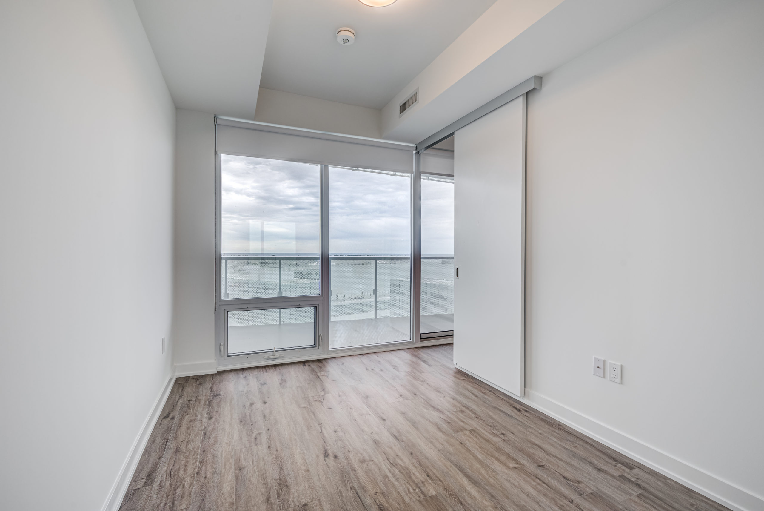 Bedroom with large windows offering Lake Ontario views.