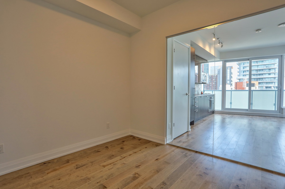 Bedroom with glass walls and view of kitchen beyond.