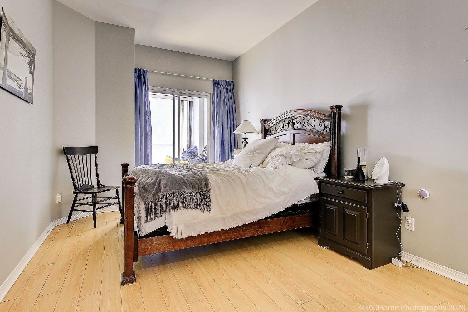 Mostly empty master bedroom of 817 - 7 King St E with large bed with dark wooden frame.