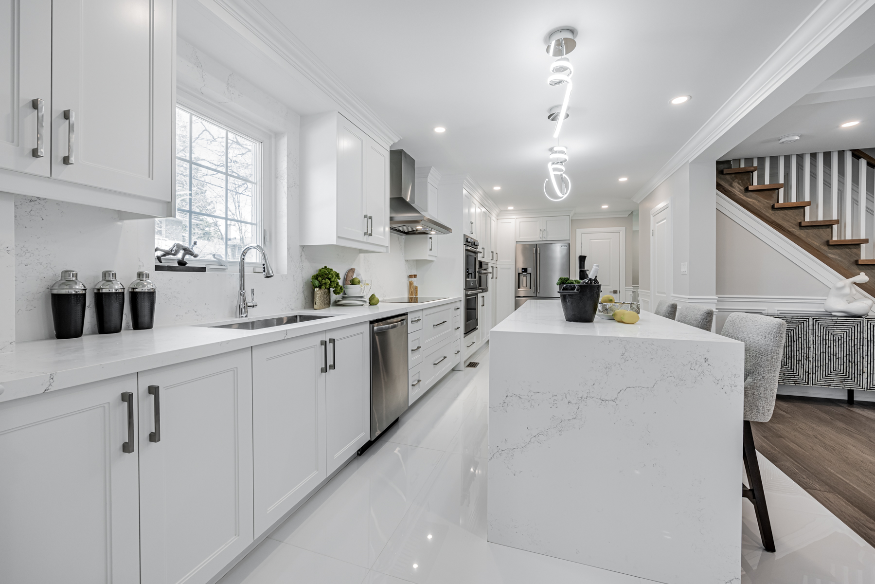 Kitchen with porcelain tiles, multiple cabinets and drawers, pot-lights and long counter.