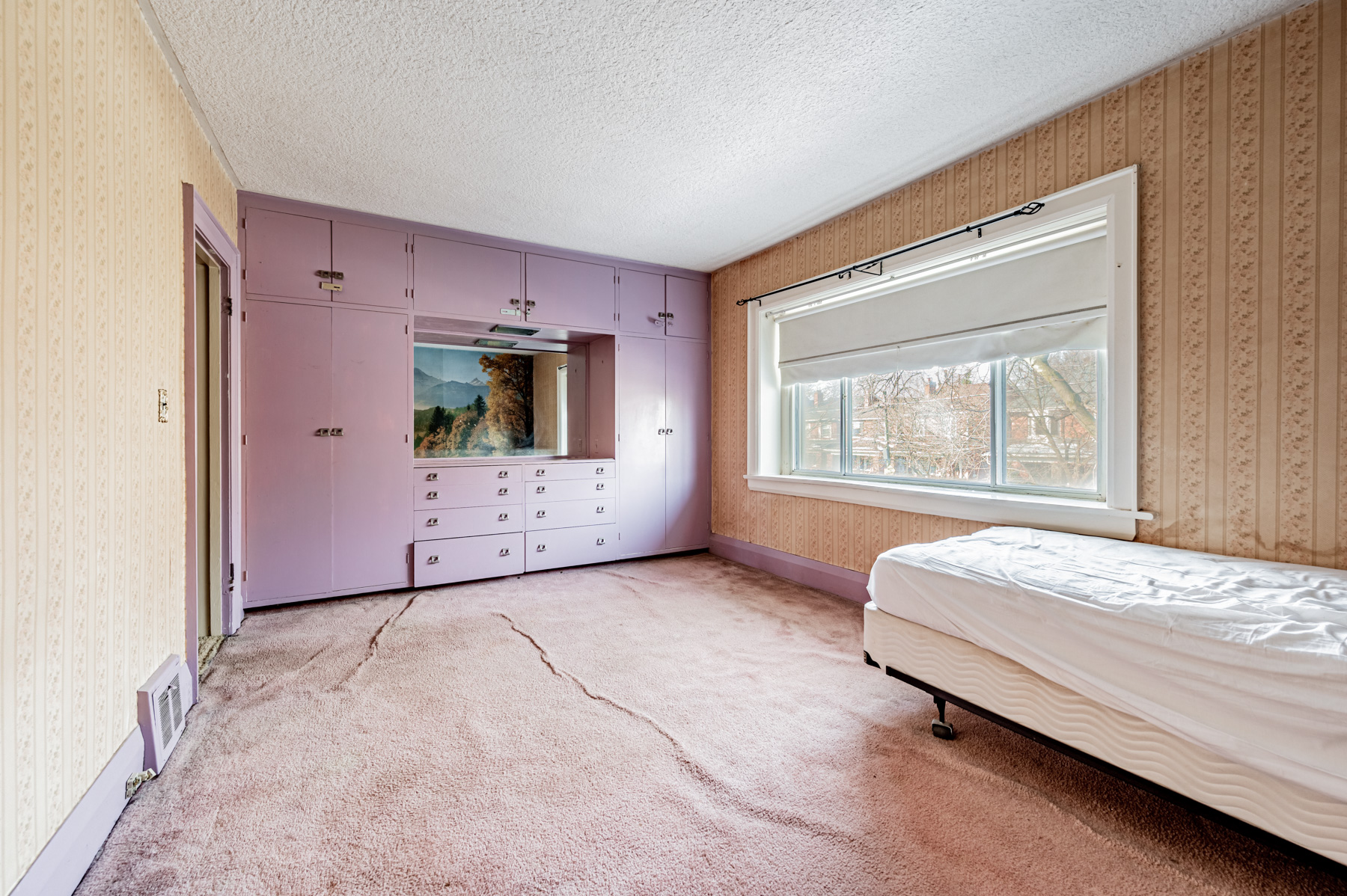 35 Woburn Ave primary bedroom with built-in purple cabinets and drawers, carpet and large window.