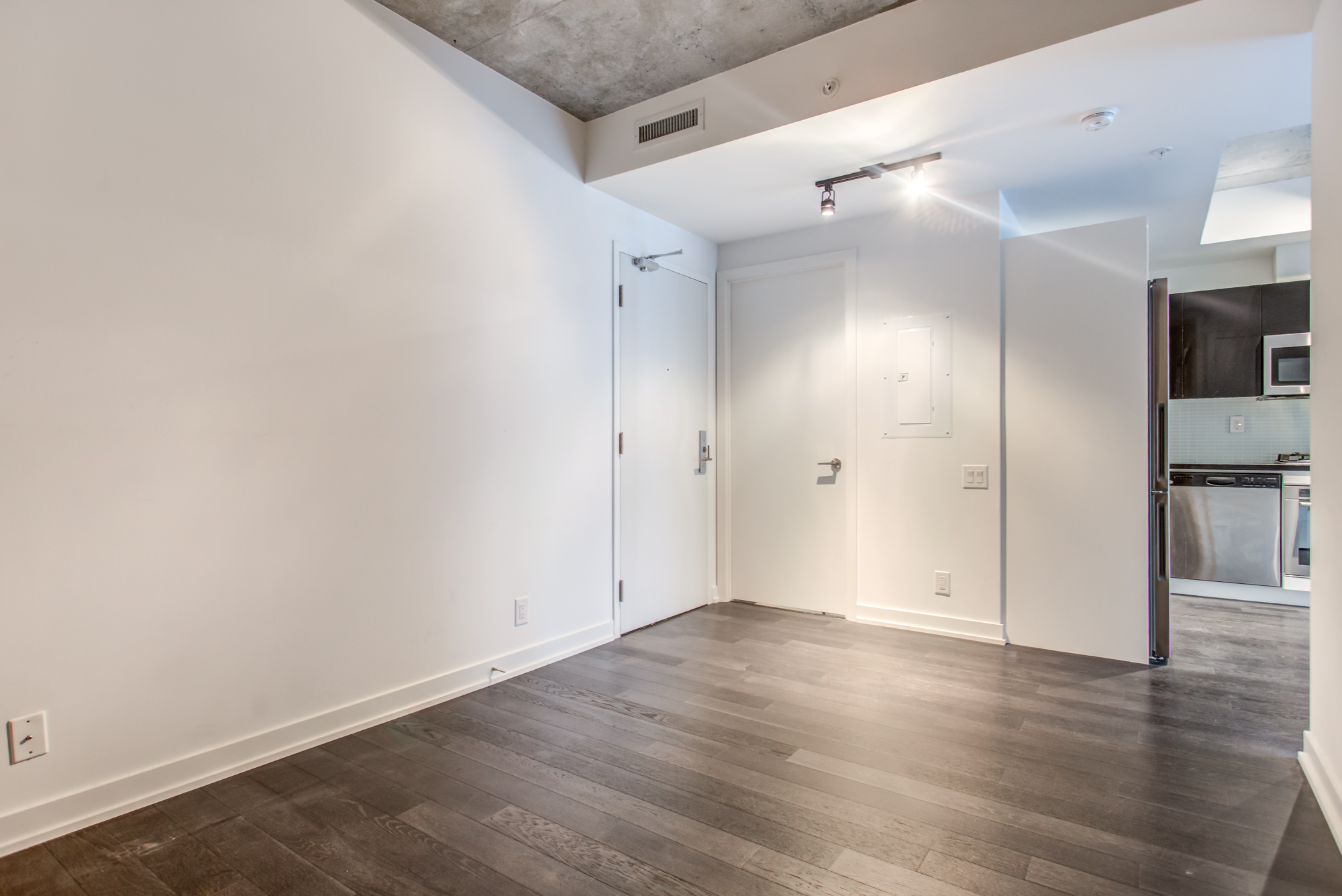 39 Brant St Unit 918, Brant Park Lofts, in Queen West, master bedroom with dark laminate floors and kitchen view.
