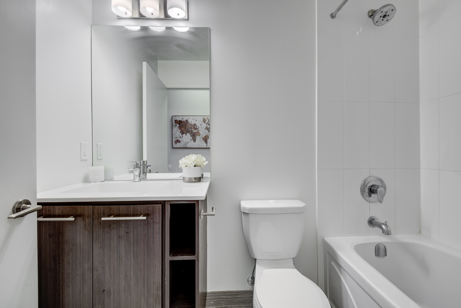 The penthouse suite washroom with toilet, bathtub, sink and dark wooden cabinets.