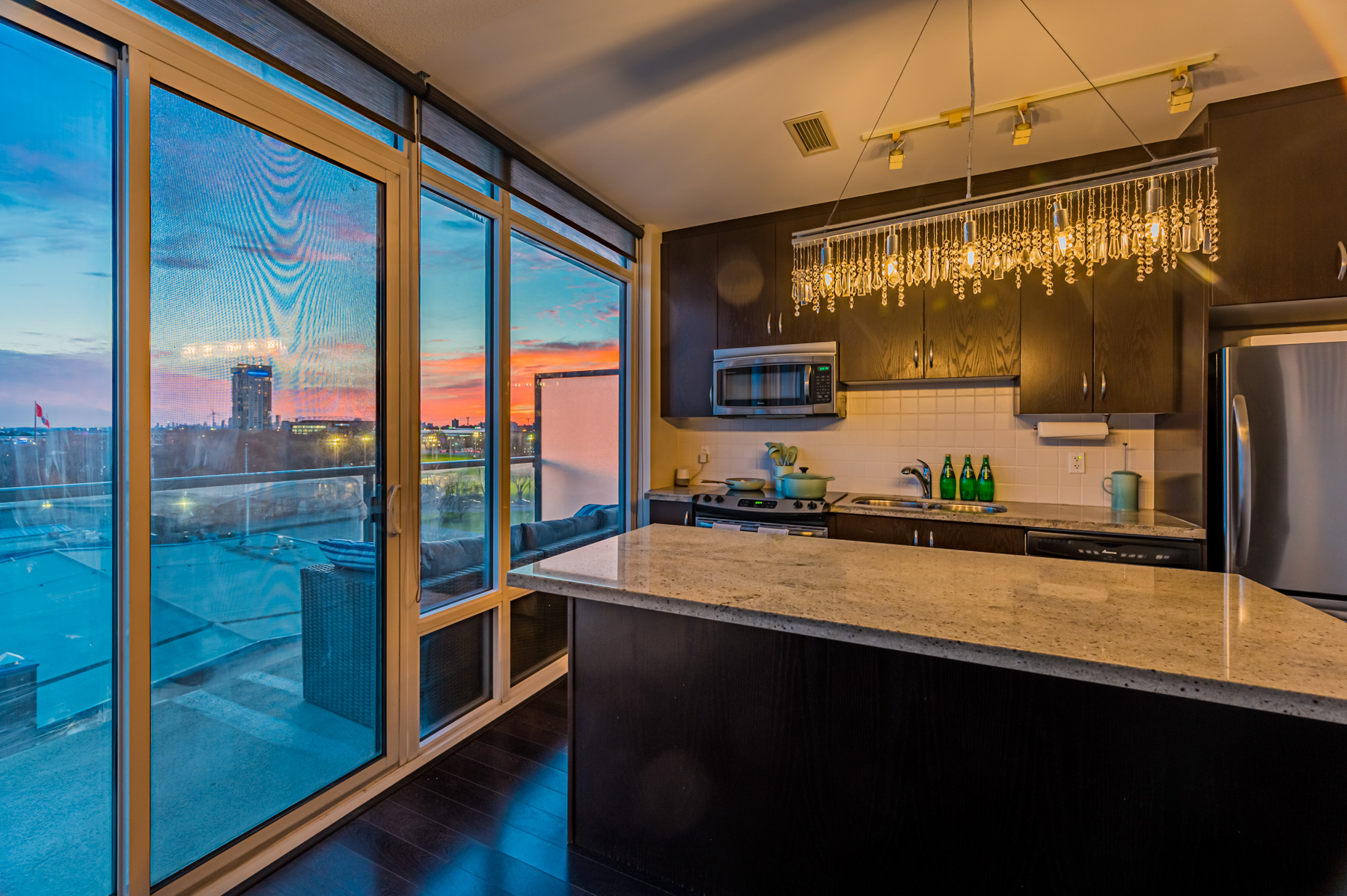 Kitchen island with chandelier and view of Lake Ontario at dusk.