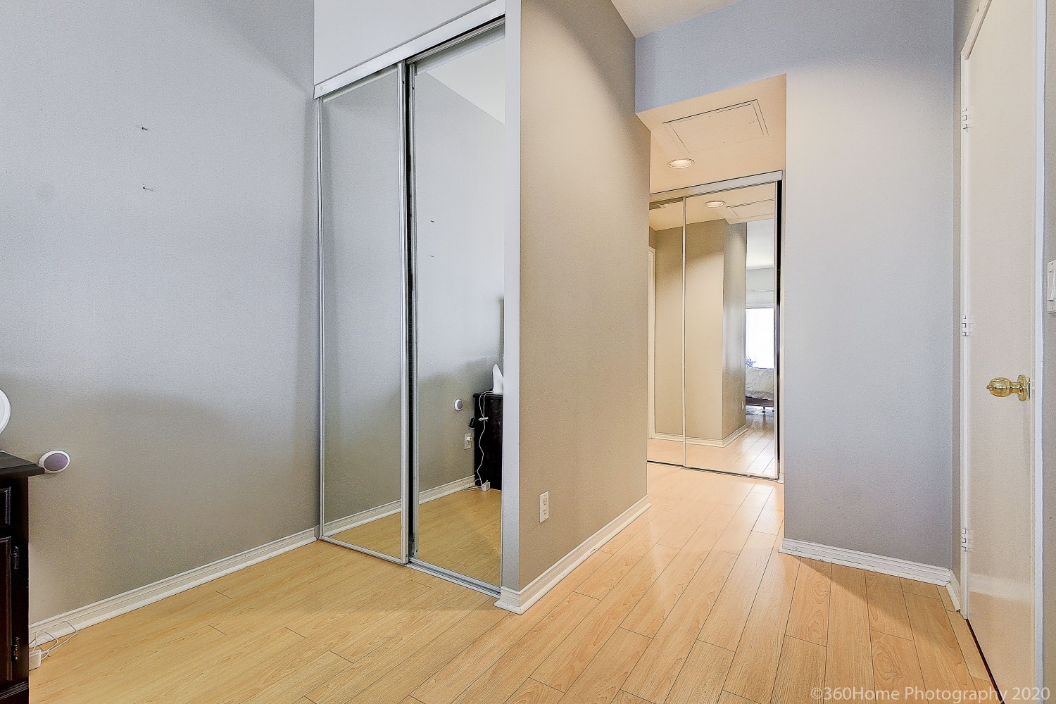 Light brown laminate floors and closet with mirror doors.