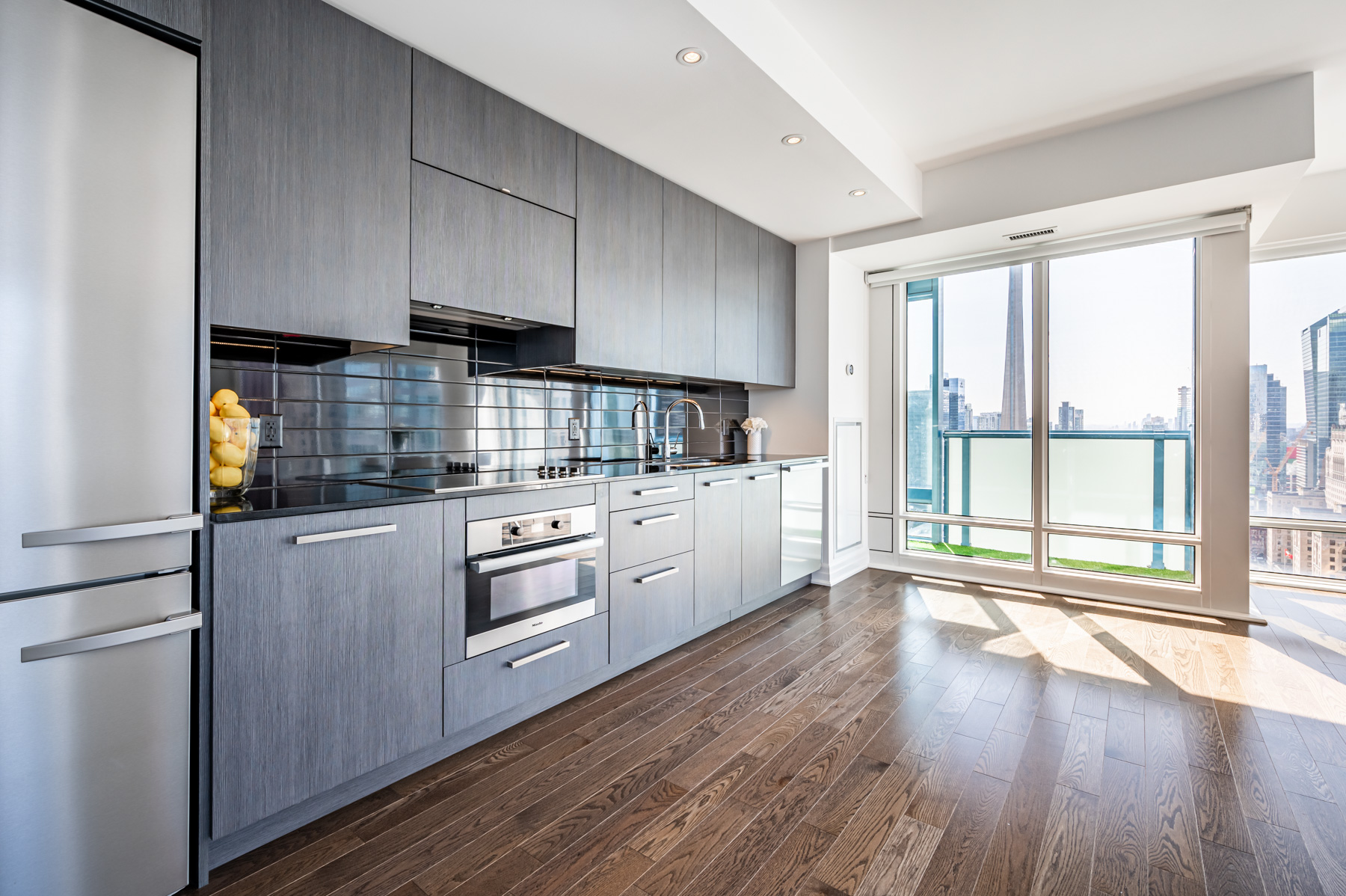 Condo kitchen with dark cabinets, counters and back-splash.