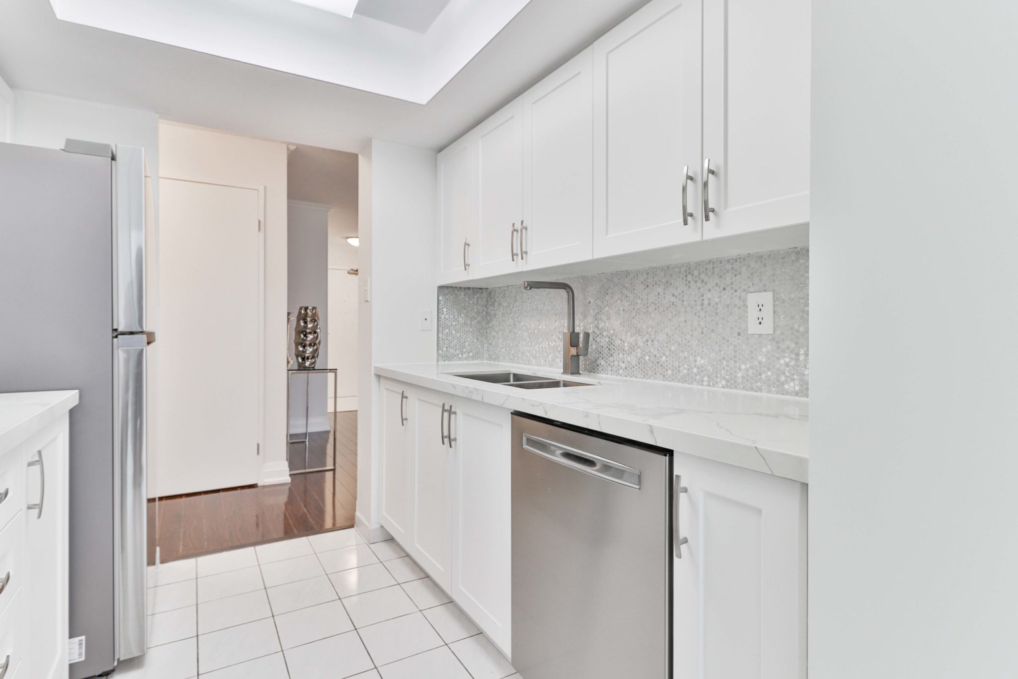 Renovated kitchen with new white cabinets, double sink and back-splash.