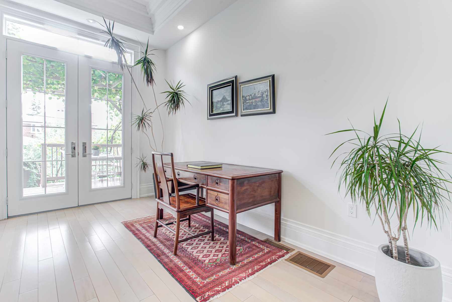 Home office with mahogany desk and plants.