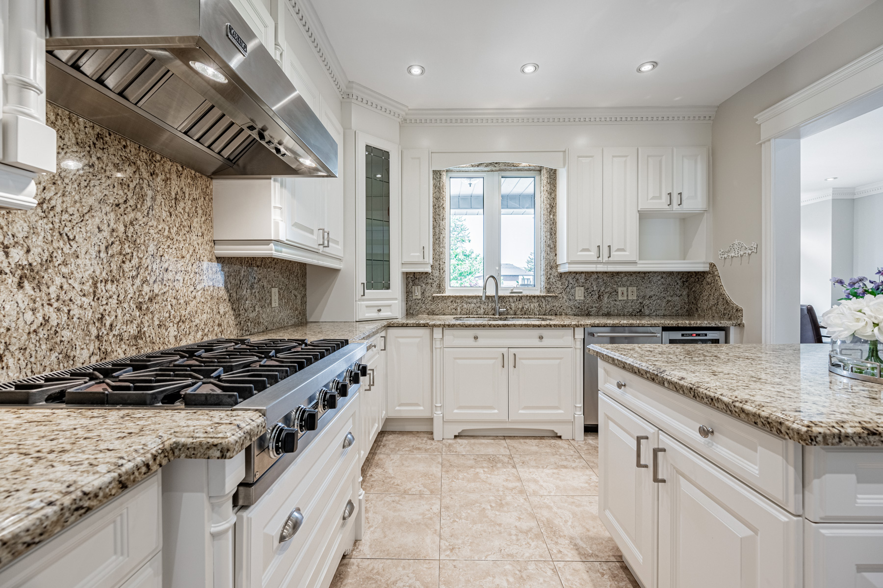 Large kitchen with speckled granite back-splashes made of single slabs.