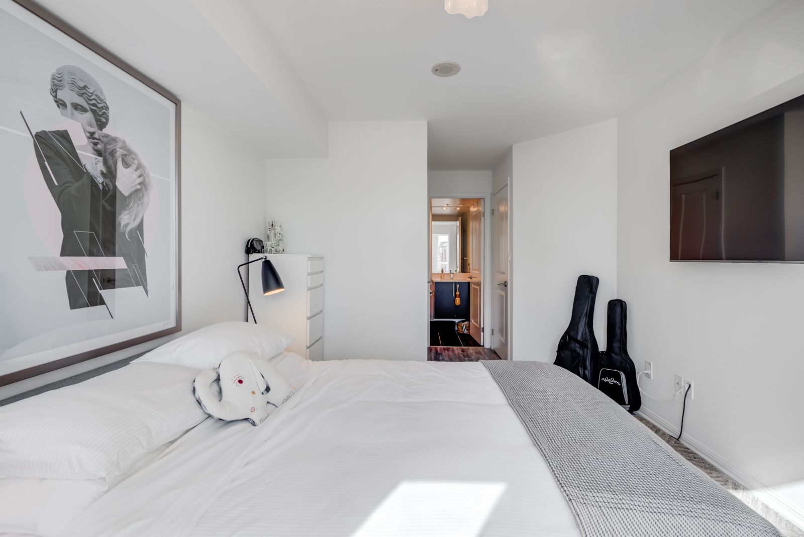 Close up of 400 Adelaide St E Unit 704 master bed with large framed black-and-white photo of woman on wall.