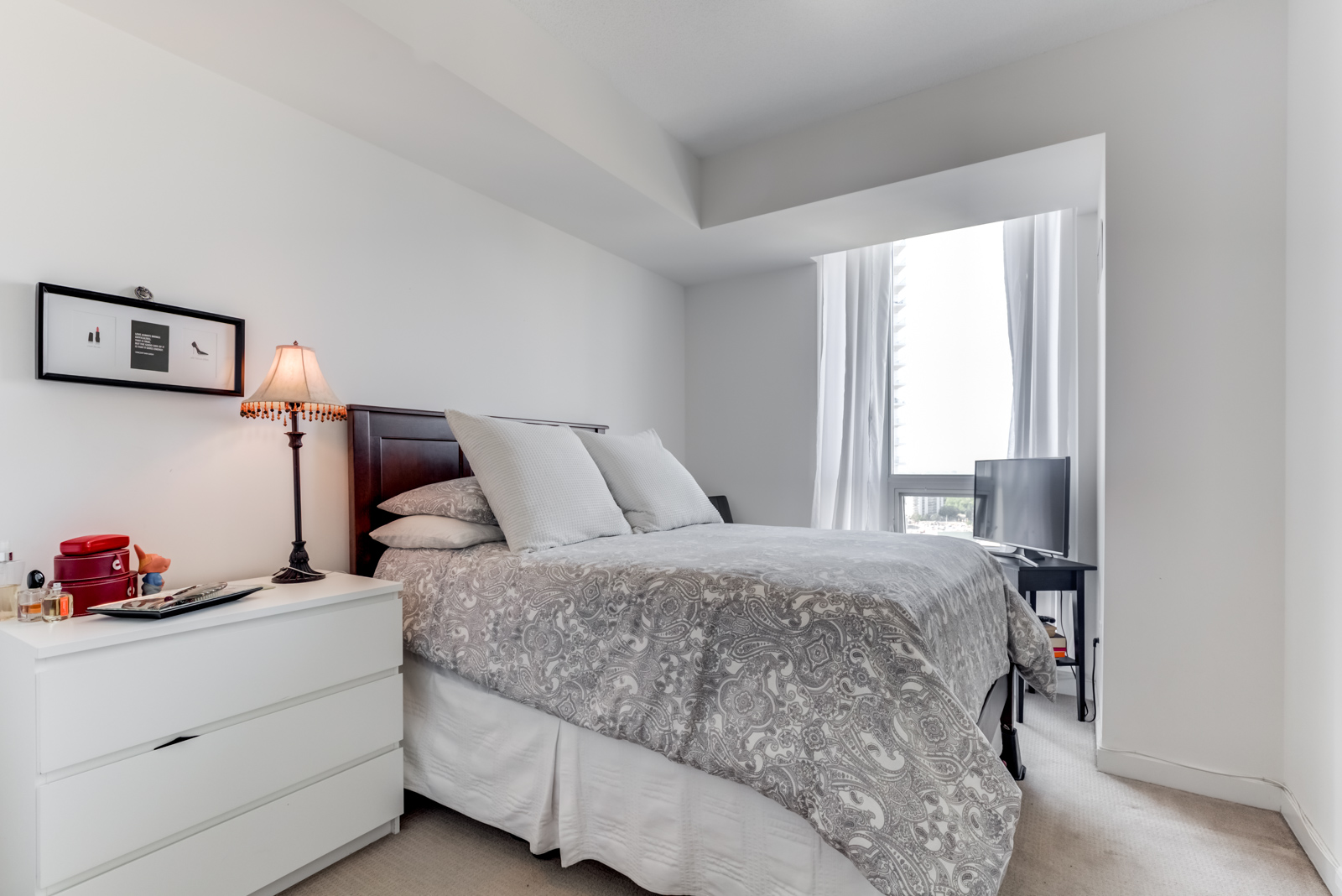 Second bedroom at 62 Forest Manor Rd Unit 1803, Toronto with large bed, gray walls, bedside table and lamp.