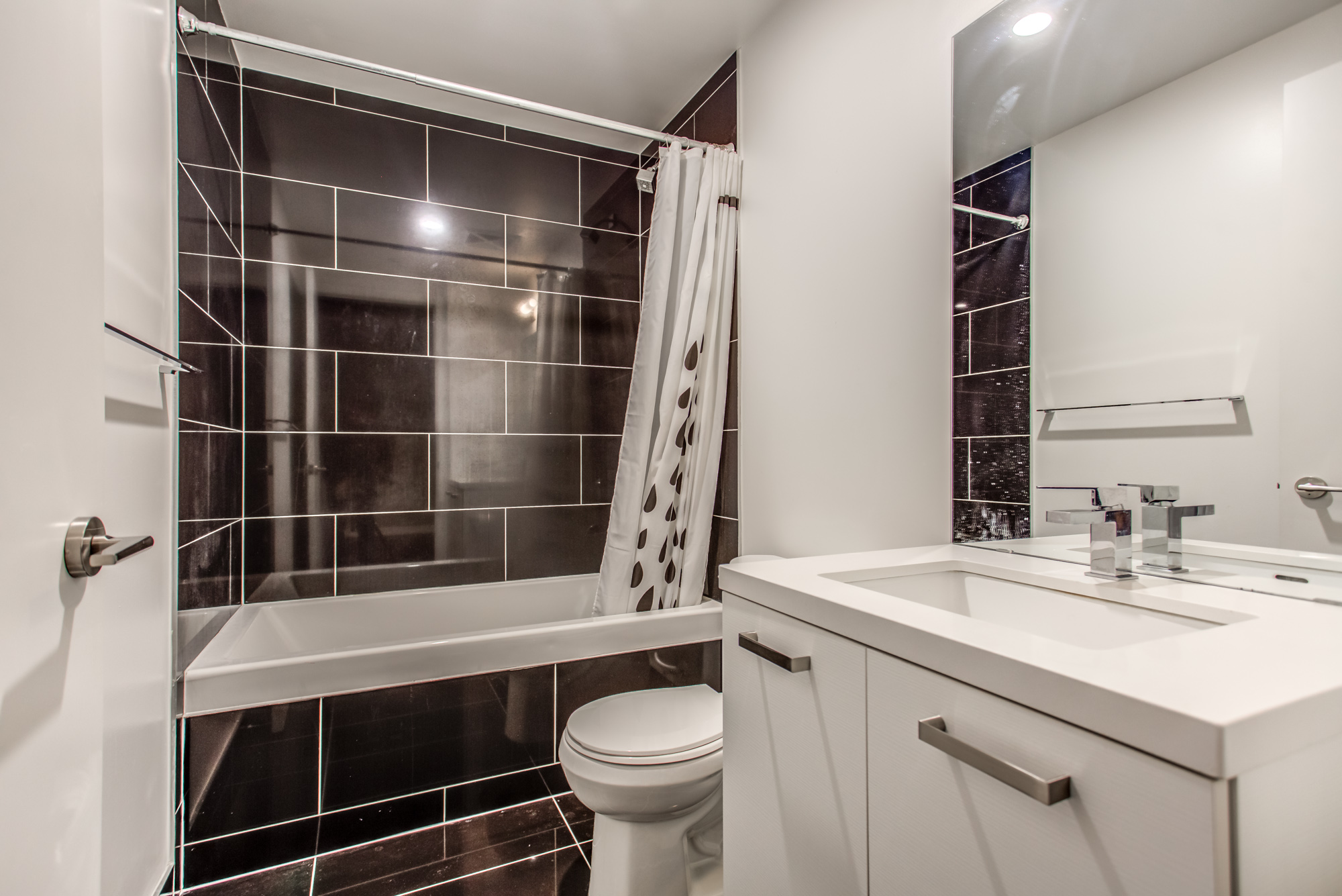 39 Brant St Unit 918 washroom with large, rectangular polished black tiles and gray and white colours.