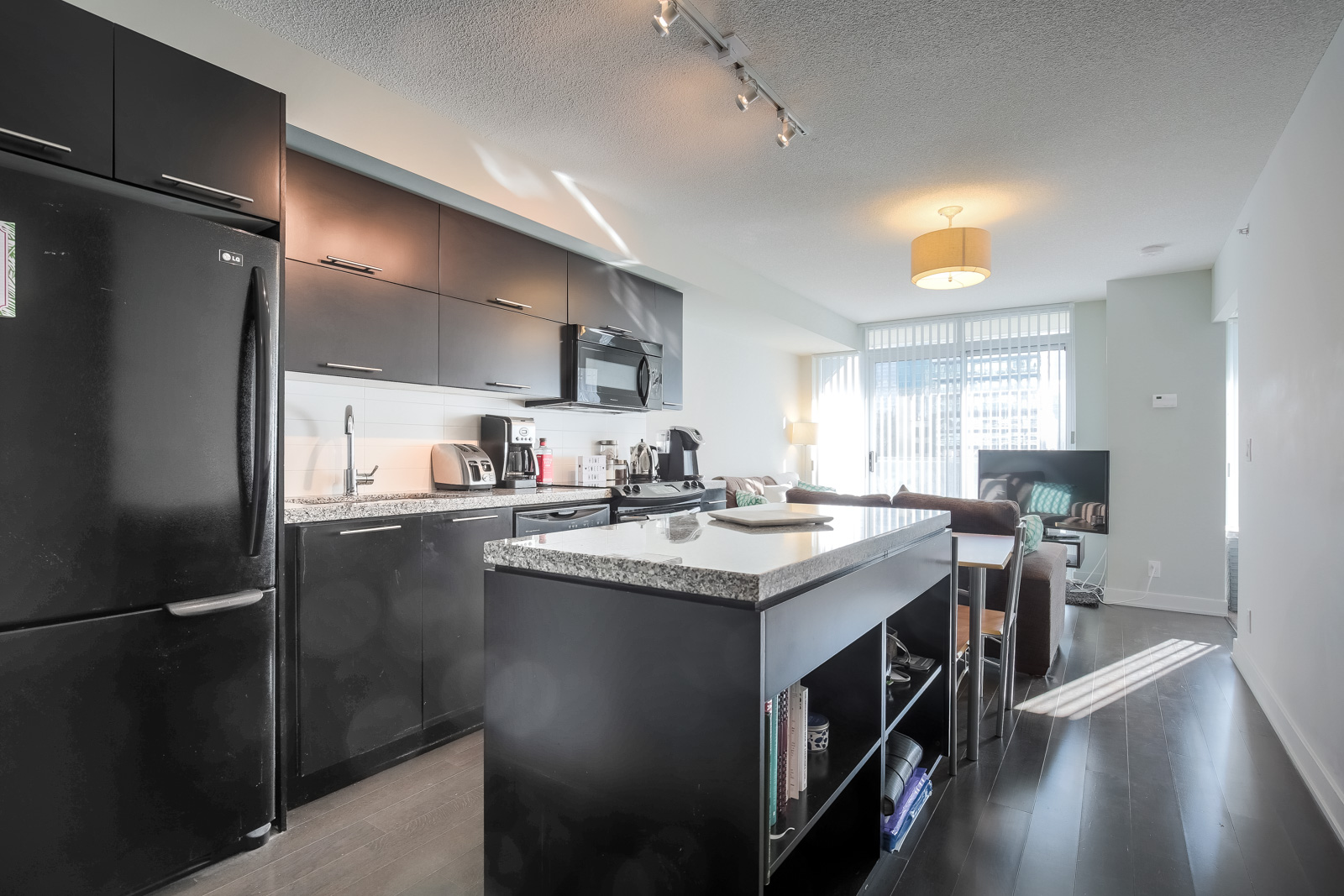 View of condo interior showing modern, open-concept design, hardwood floors & stainless steel appliances