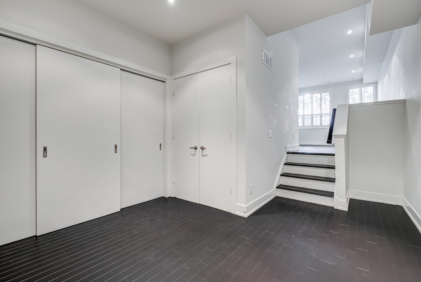 Empty basement rec room with hardwood floors