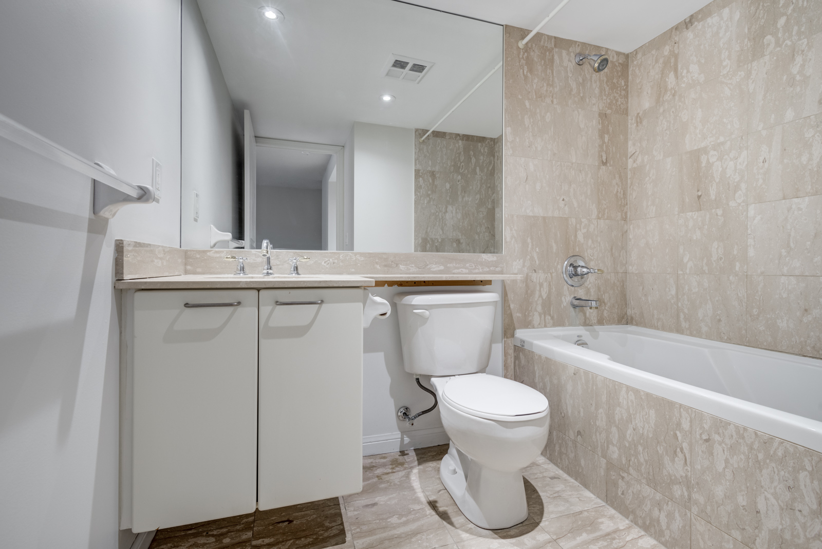 4-piece bathroom with beige tiles, tub, sink and large mirror.