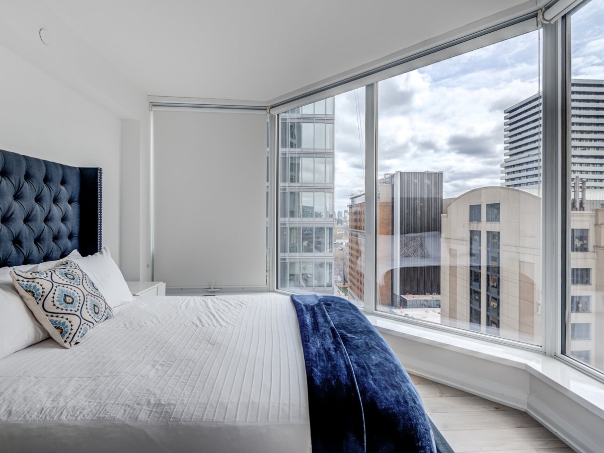 Master bedroom with large bed and view of city from large windows.
