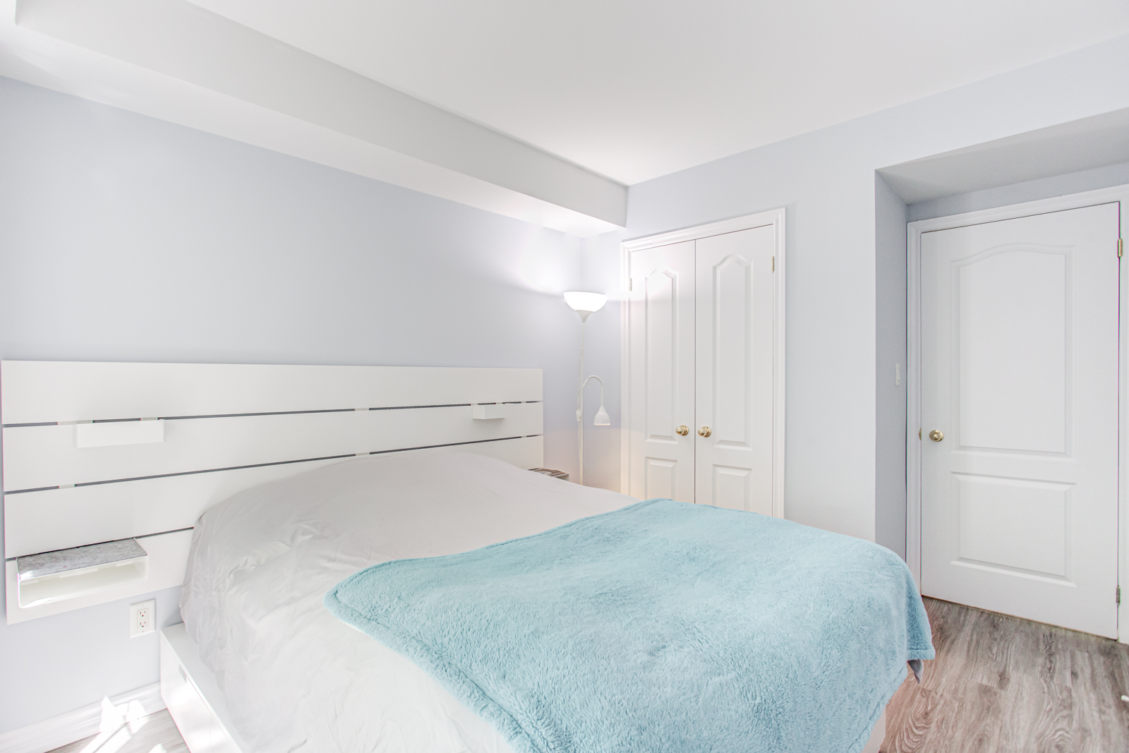 Alternate angle of master bedroom showing mostly white and gray color scheme.