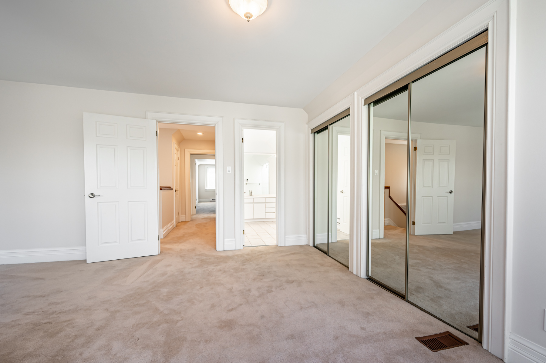 Bedroom with his and her closets with sliding mirror doors.