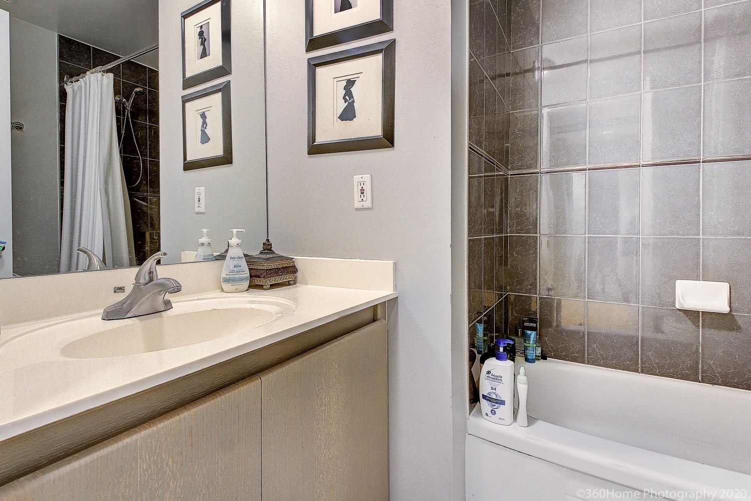 7 King St E ensuite bath black shower tiles, framed photos and white counter.