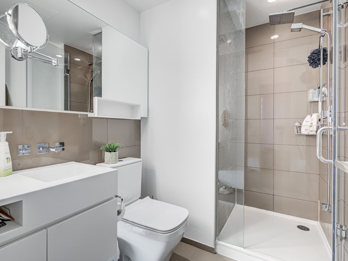 Bathroom with standing shower, Corian counters, large vanity with magnifying mirror, rain-shower, and hand-held faucet.