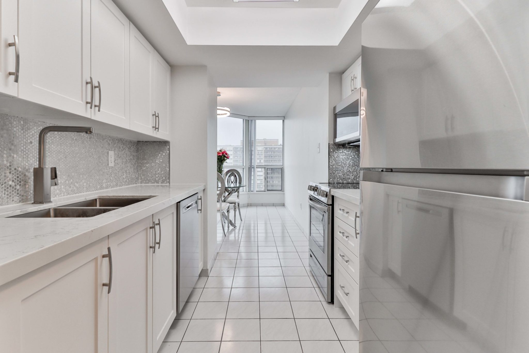 Walk-through kitchen with white quartz counter-top and chic faucet.