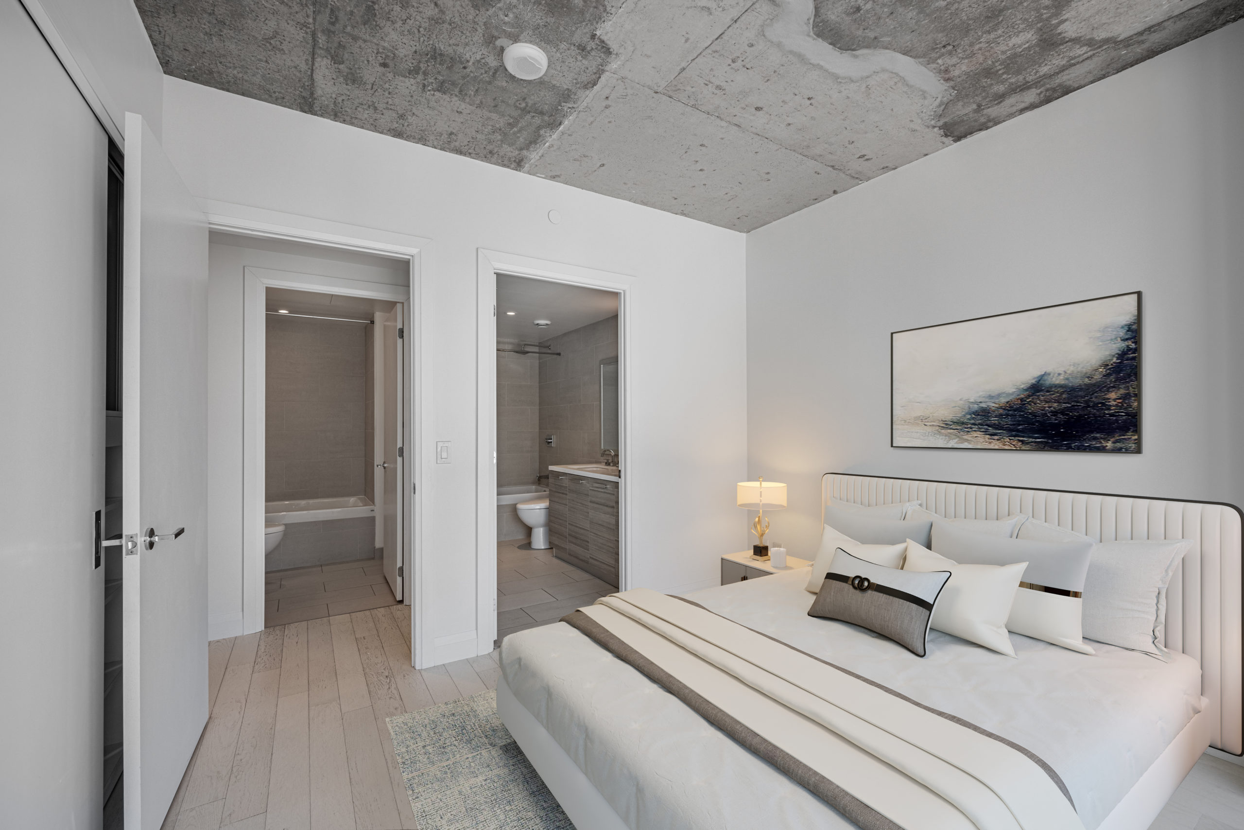 Condo bedroom with hardwood floors, gray walls and exposed concrete ceiling.