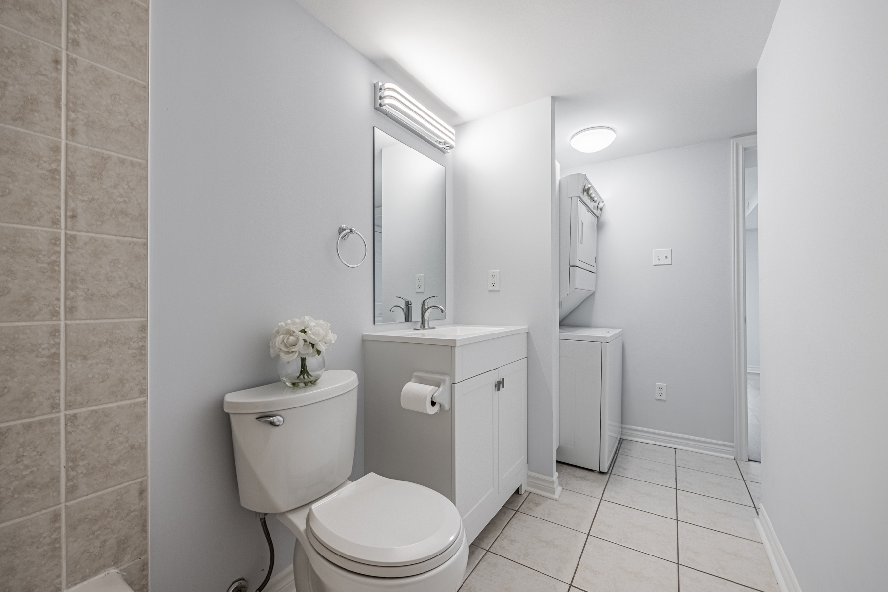 Bathroom next to laundry with stacked washer and dryer.