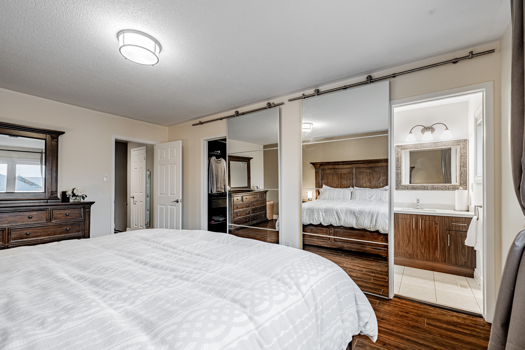 Walk-in closet and ensuite bath with mirror doors.