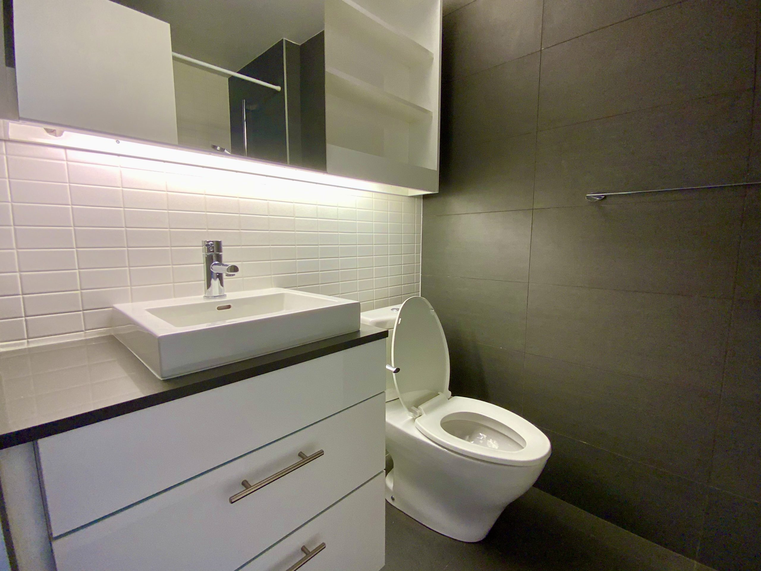 Modern bathroom with black and white tiles, raised sink bowl and wall-mounted shelves.