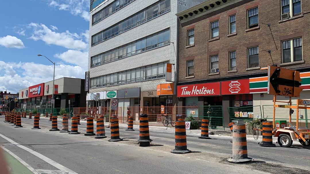 Black and orange construction cones, fence and Tim Hortons storefront on Bathurst and Bloor West in The Annex.