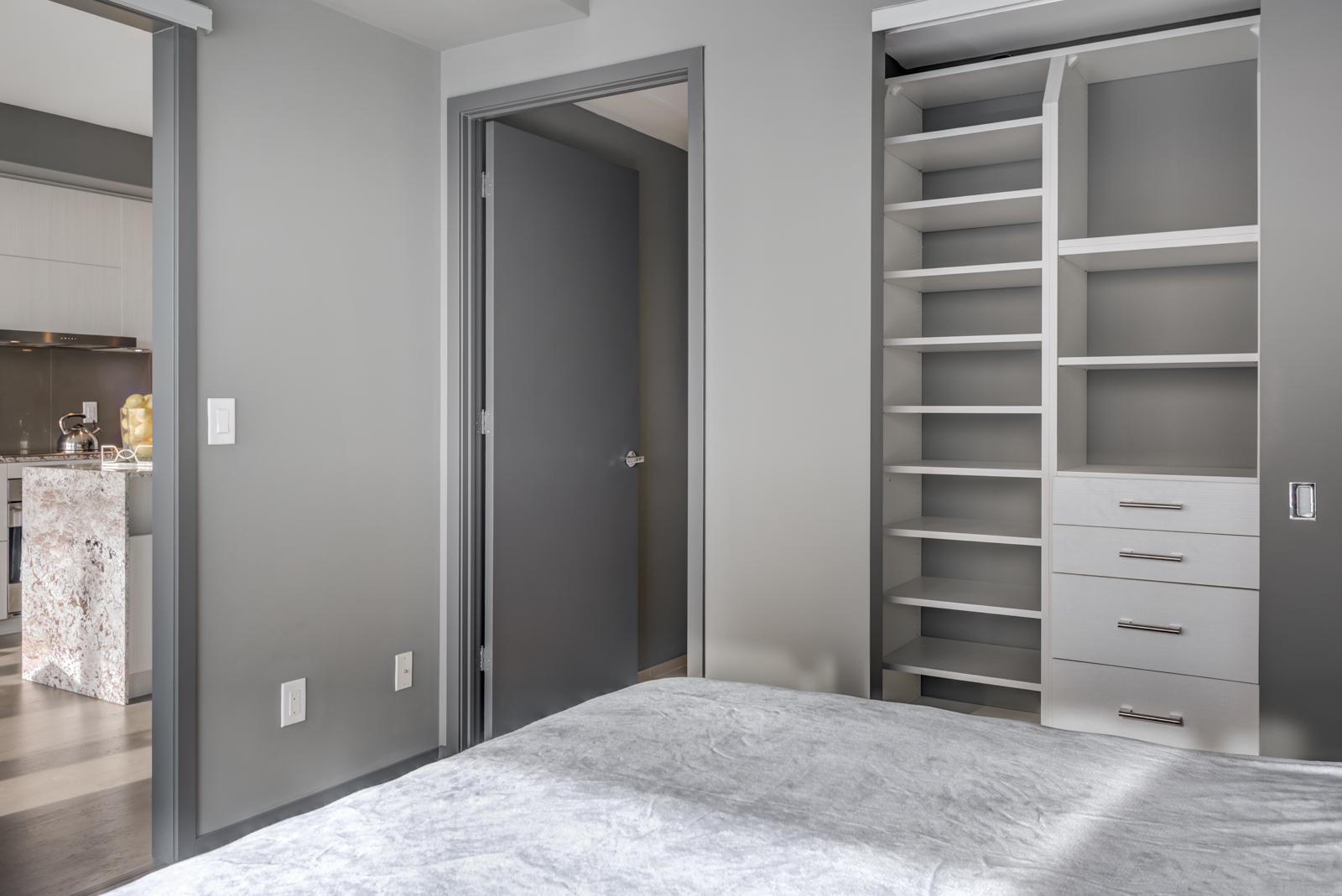 Open closet doors with empty shelves and drawers in bedroom of Unit 4305.