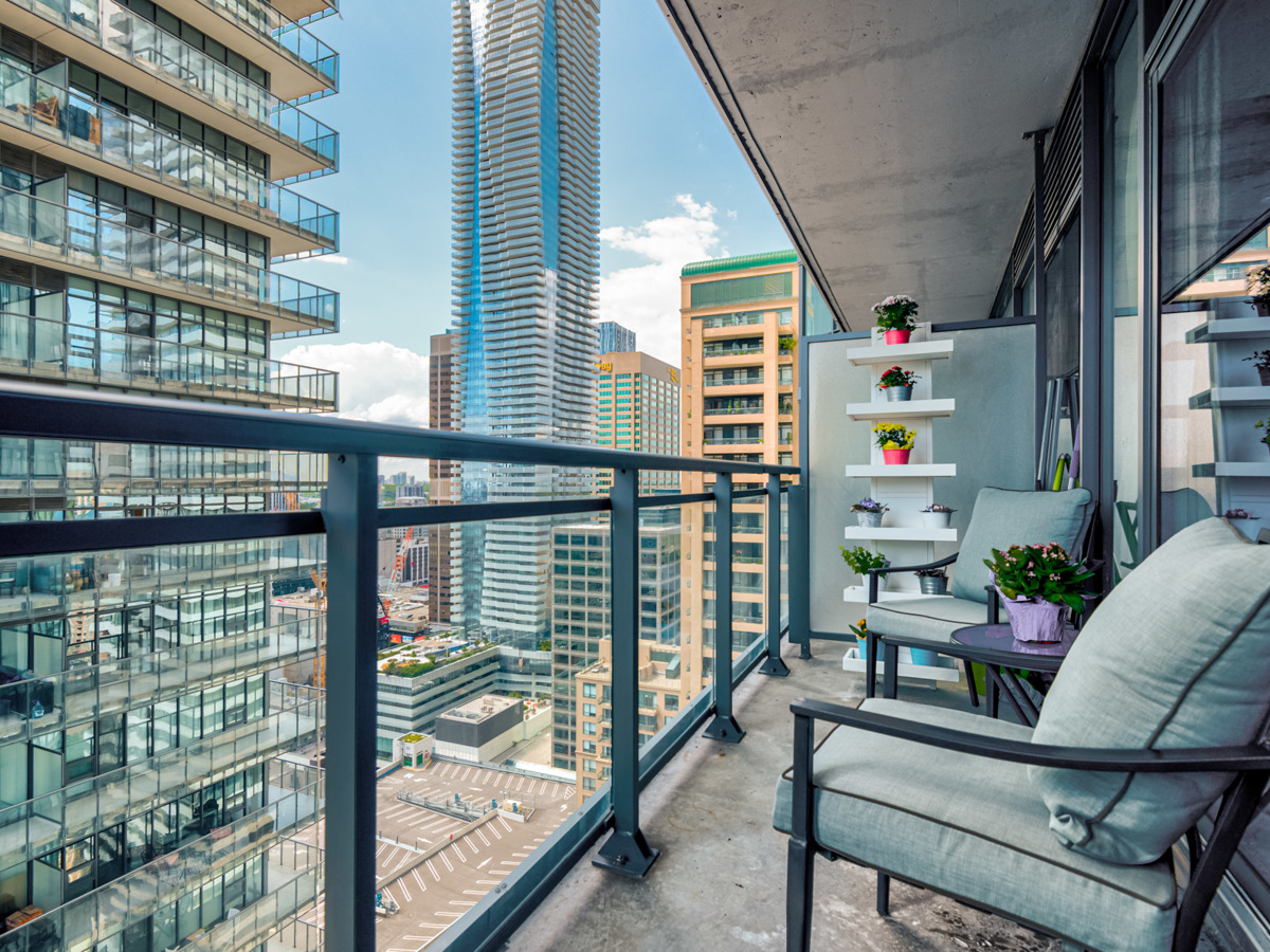 45 Charles St E balcony with bistro set and transparent glass panels.