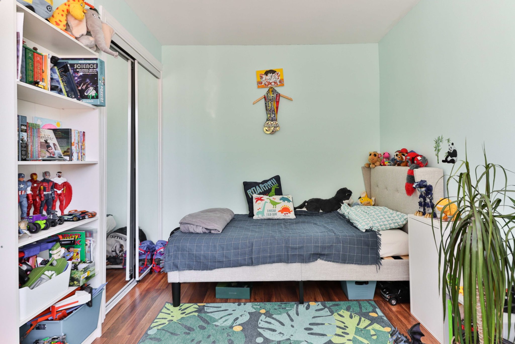 Boy's bedroom with toys on bookshelf and toys under bed.